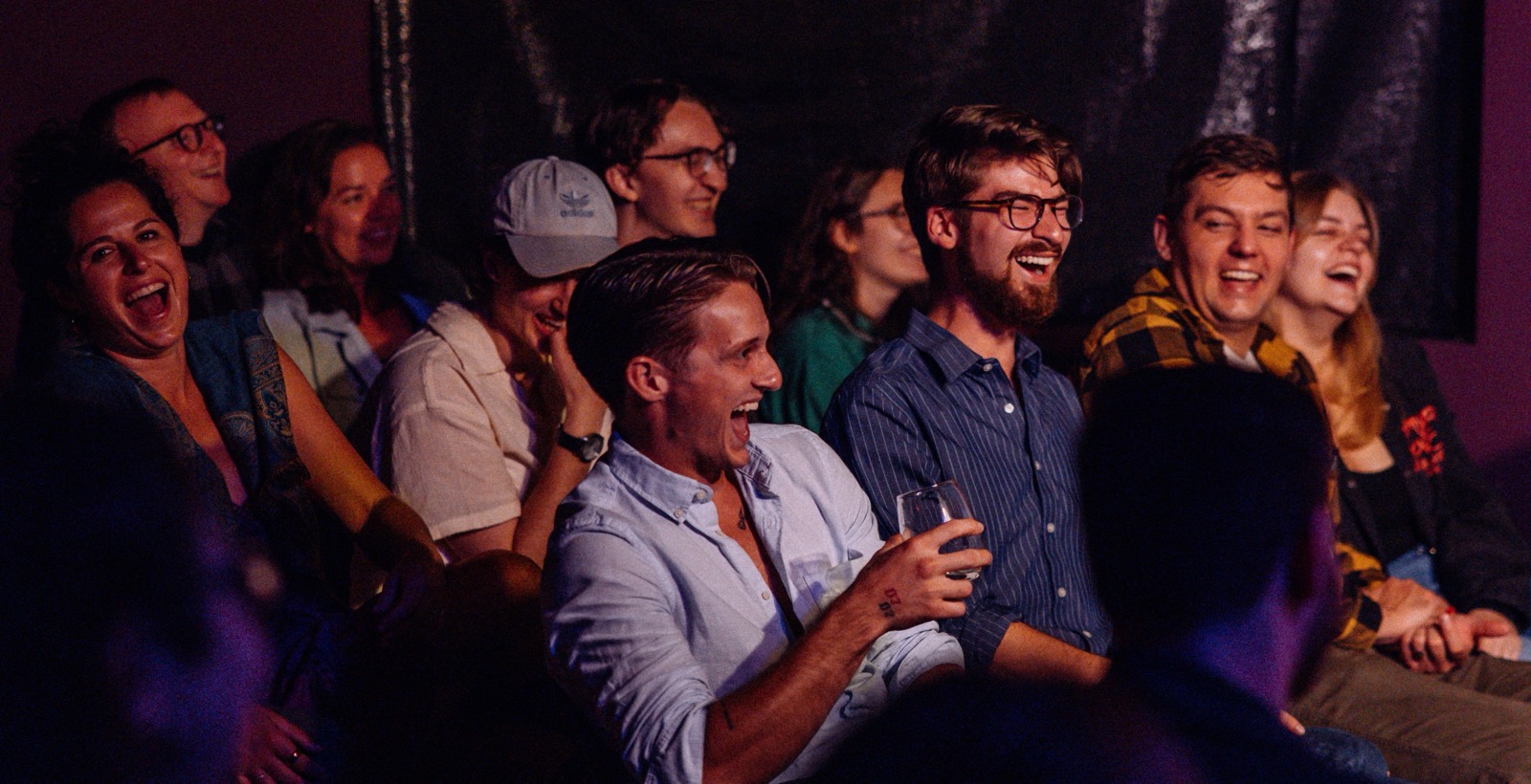 A packed, dimly lit comedy club audience mid-laugh at Goofs Comedy Club
